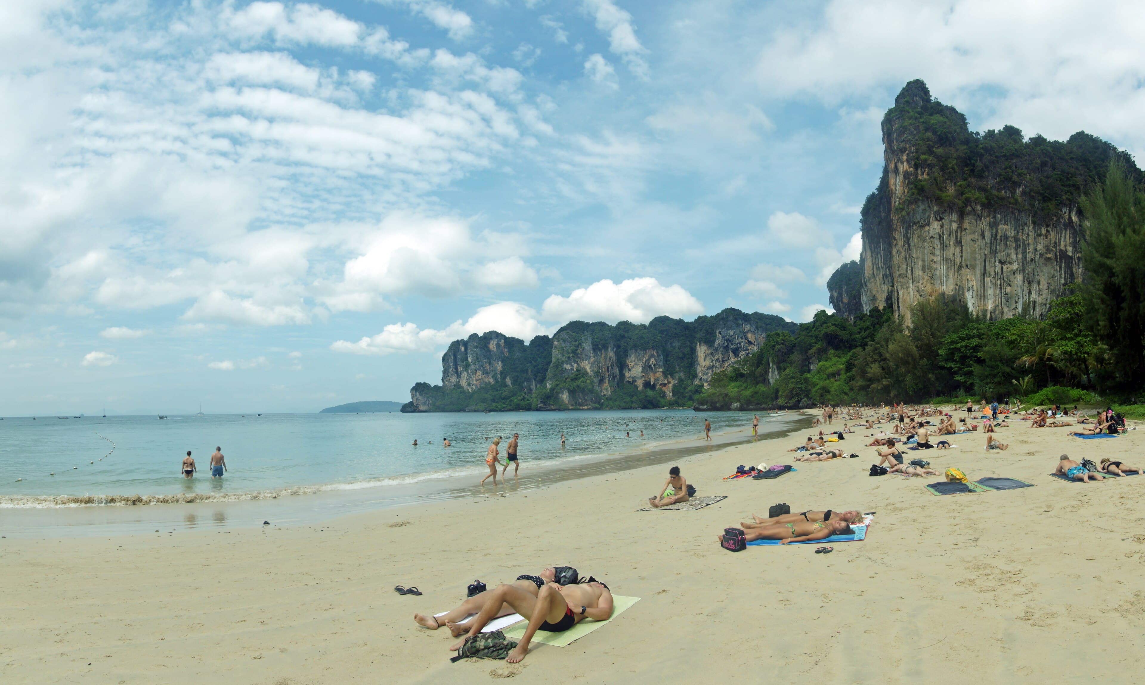 Longtail boats moored below limestone cliffs at Railay Beach, Thailand.